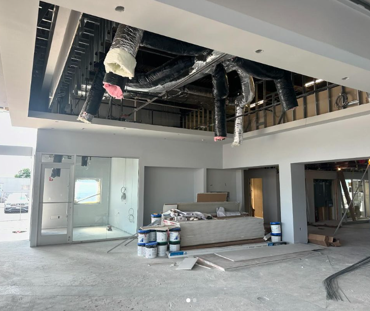 Interior construction site with exposed ducts, drywall, and paint cans.