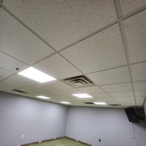 Room interior with white tiled ceiling, recessed lights, gray walls, and a vent.