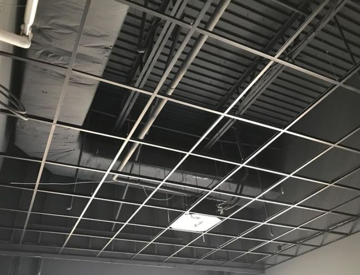 Suspended ceiling grid with exposed ductwork and a square light fixture.