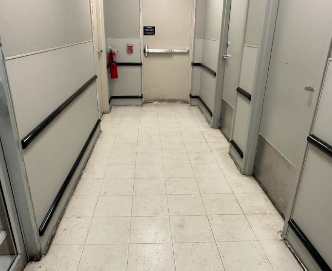 Hallway with white tiled floor, doors, and a fire extinguisher.