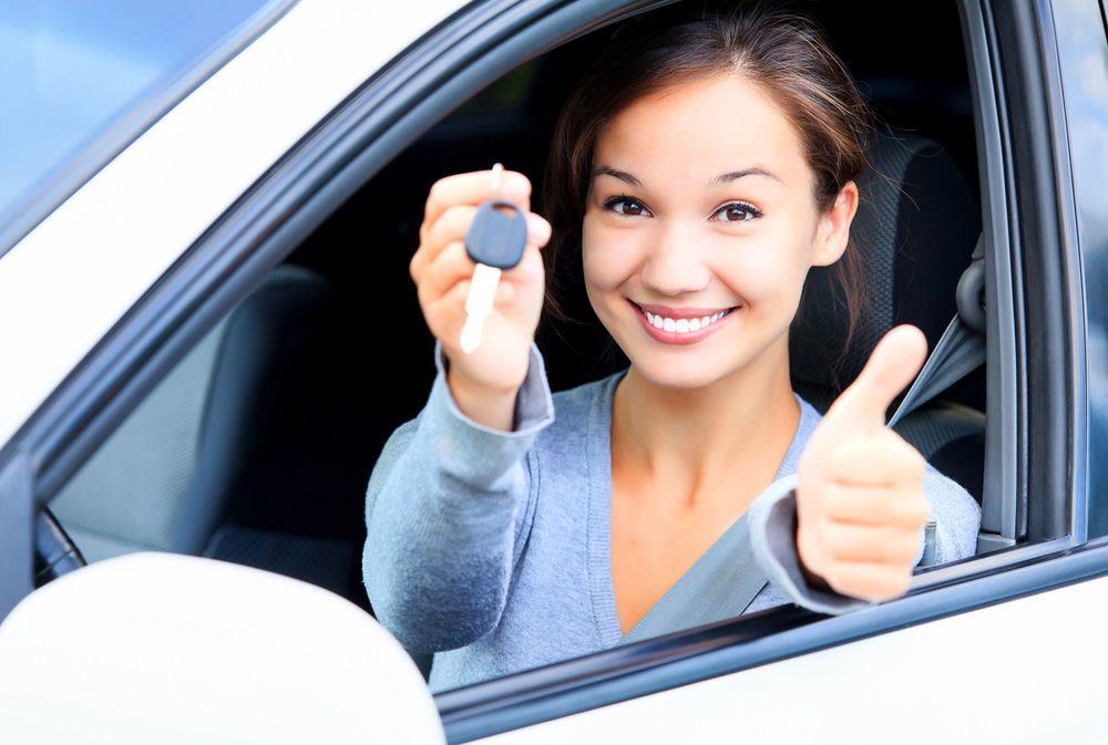 Happy girl in a car showing a key and thumb up — Locksmith in Clear Island Waters, QLD