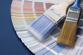 Paintbrushes rest on a color swatch fan, showing paint samples.