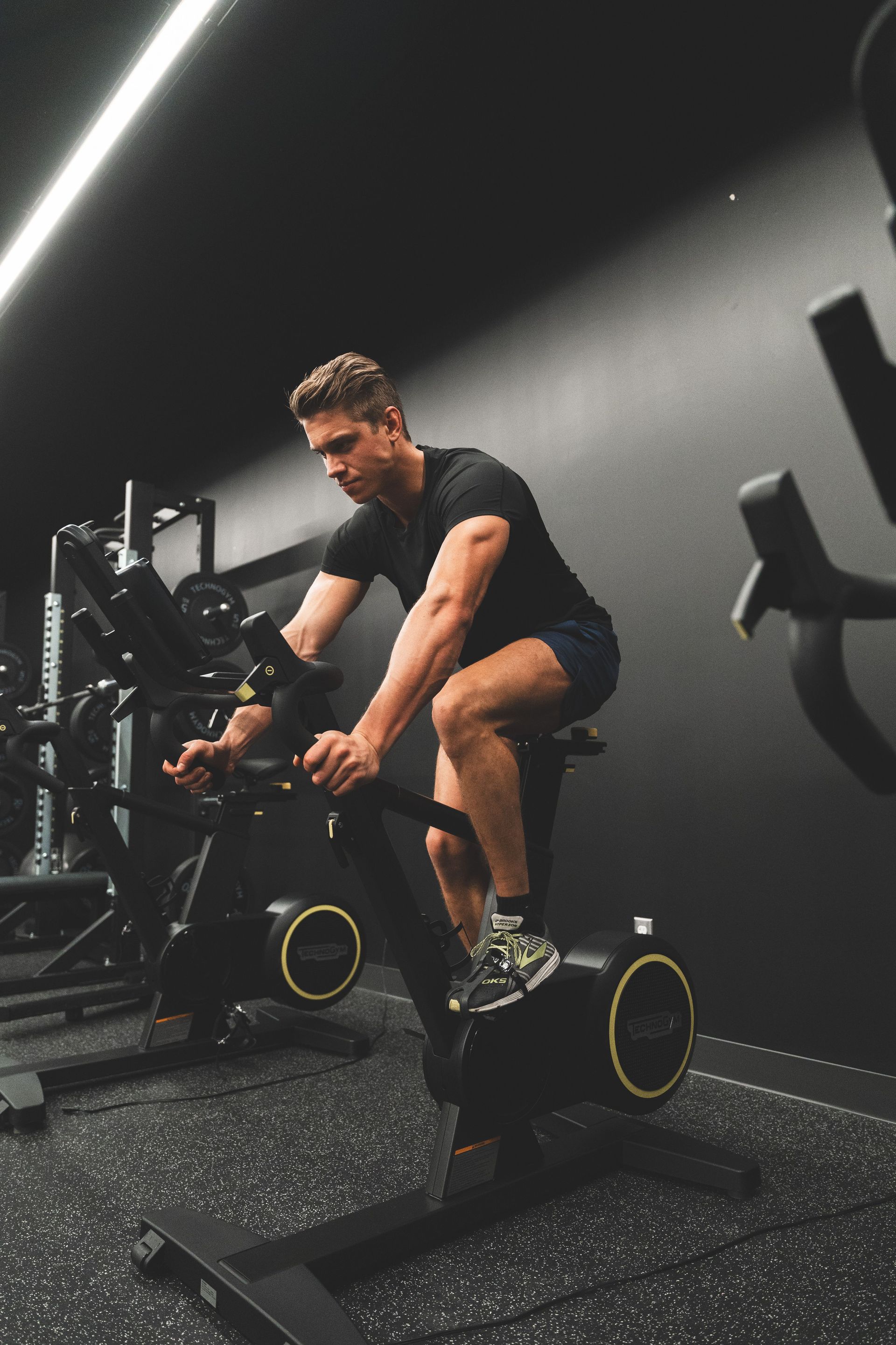 Person exercising on a stationary bike in a dim gym.