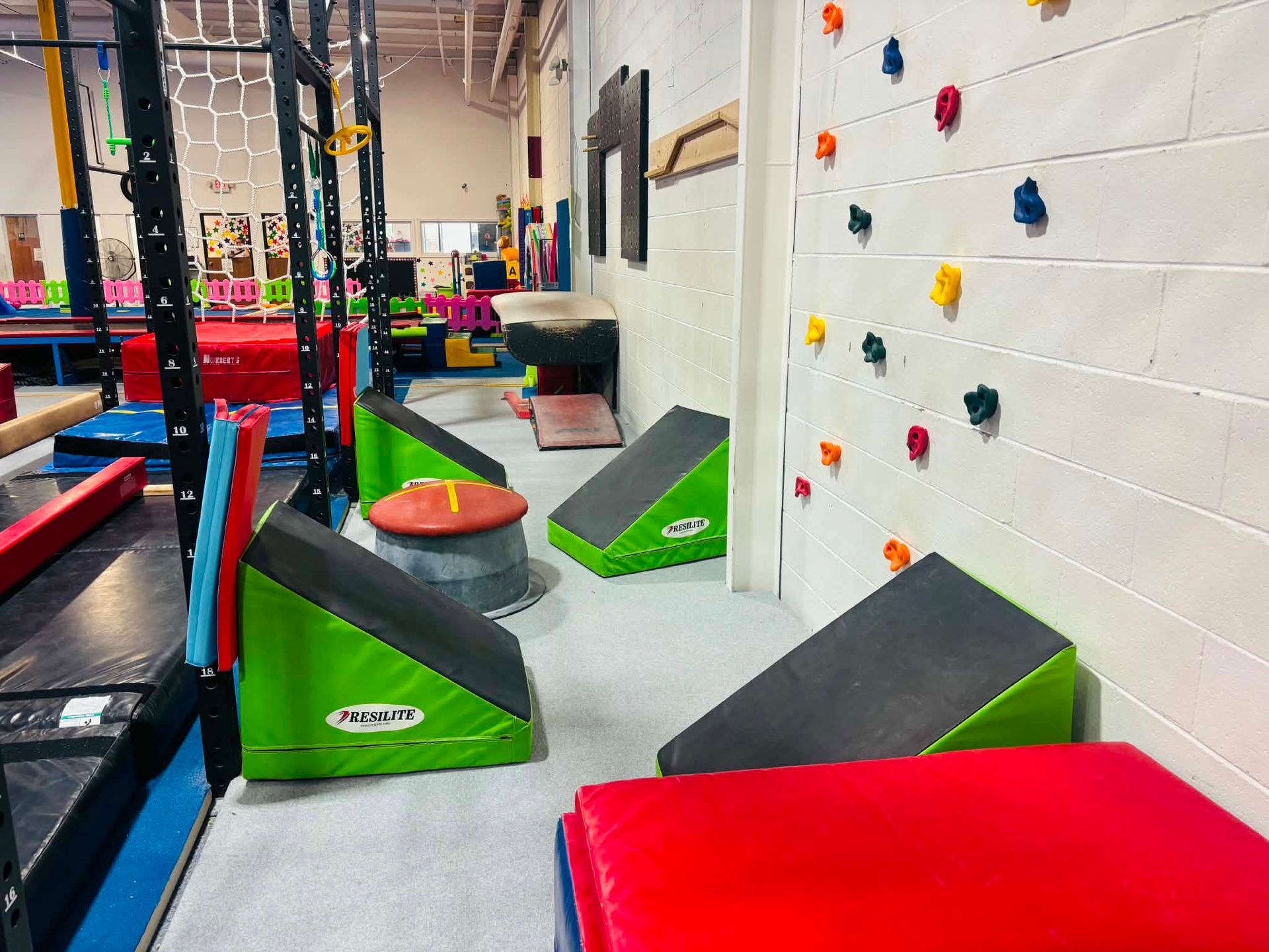 Indoor ninja gym with padded obstacles, climbing wall, and colorful blocks.