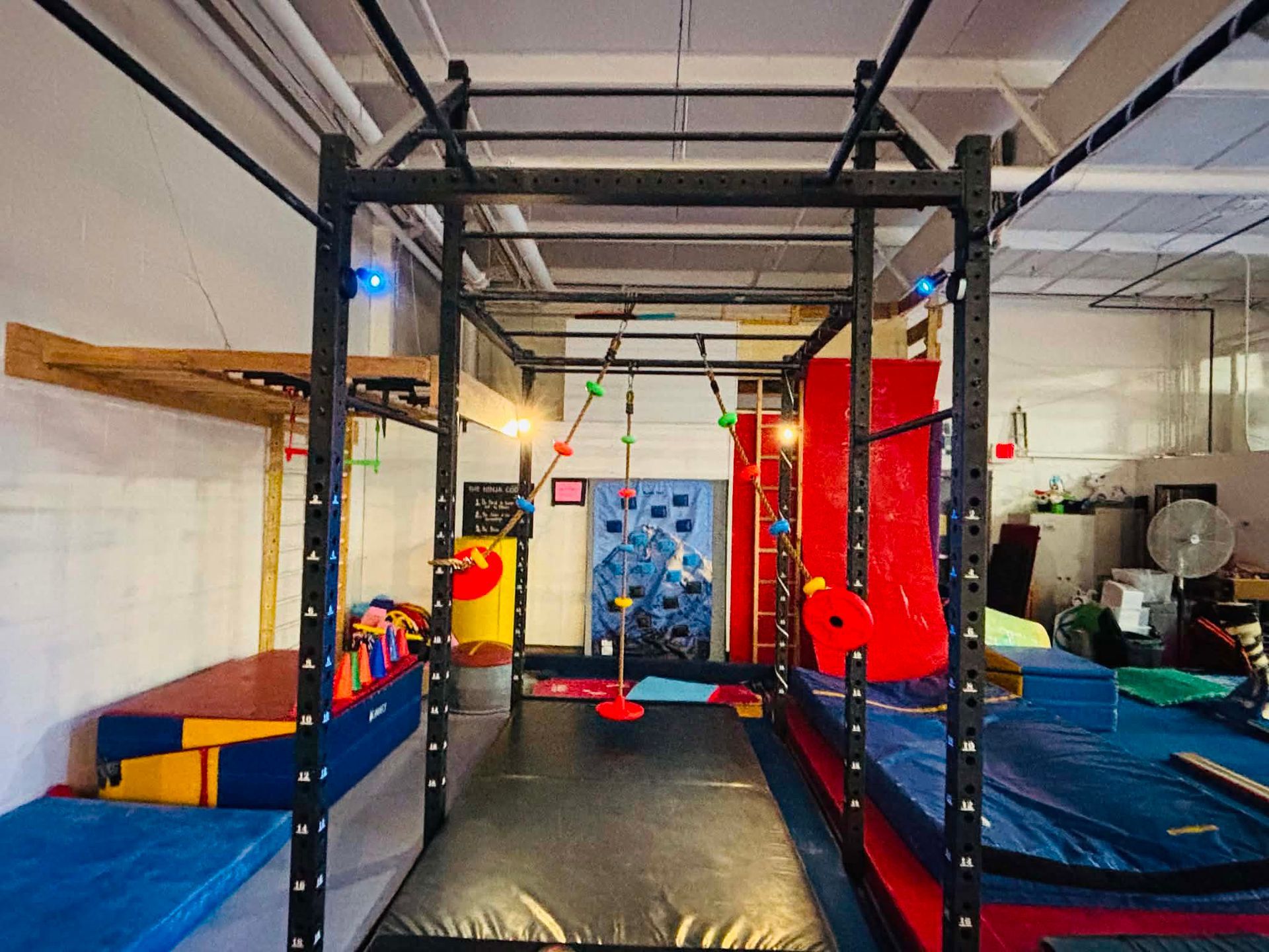 Indoor gymnastics/play area with foam pit, climbing frames, and colorful padded equipment