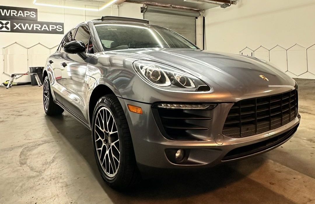 Porsche Macan with premium car wraps vinyl by XWRAPS Los Angeles, showcasing sleek silver finish and luxury detailing in high-end auto studio