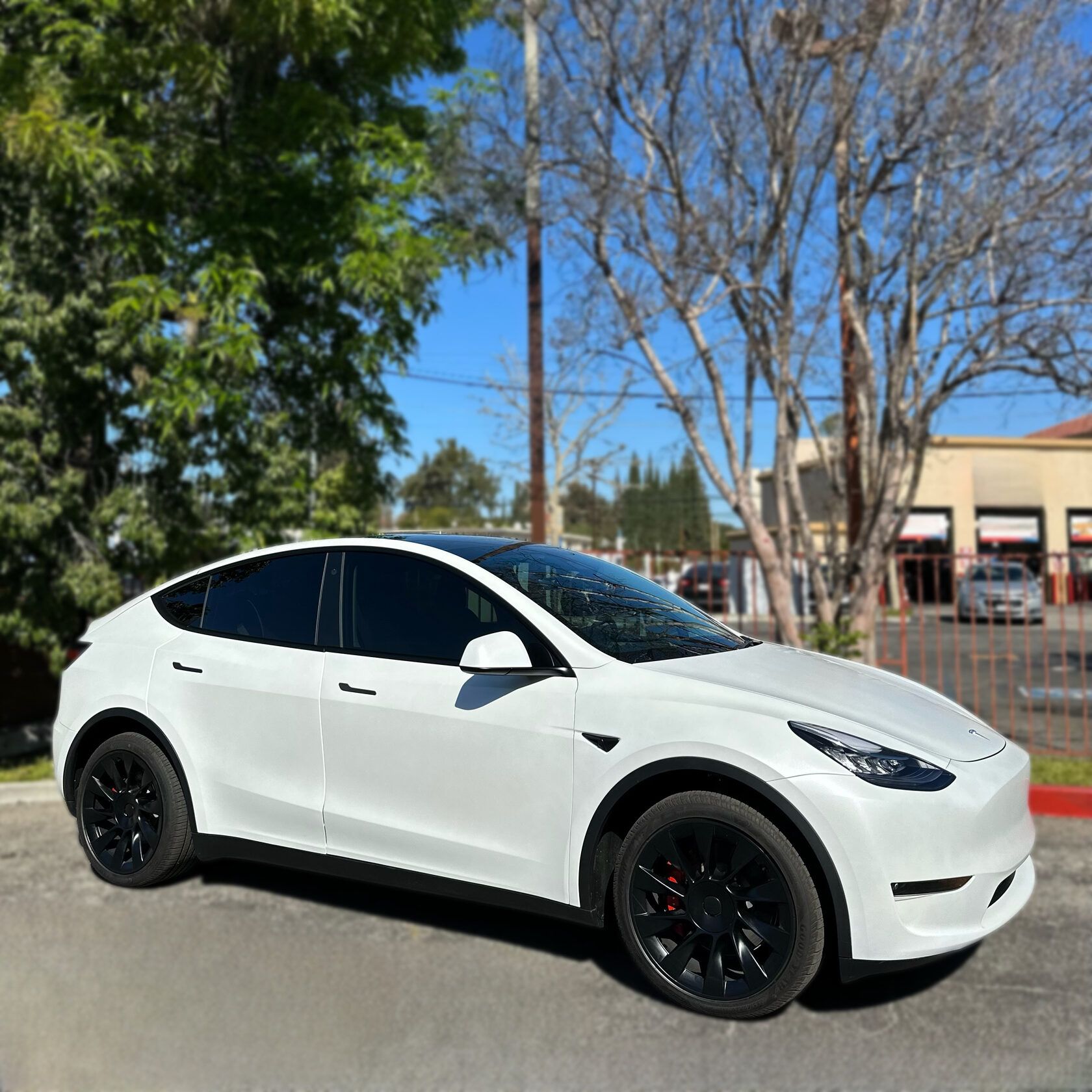 Tesla Model Y with premium car wraps vinyl by XWRAPS Los Angeles, showcasing sleek white finish and tinted windows in urban setting