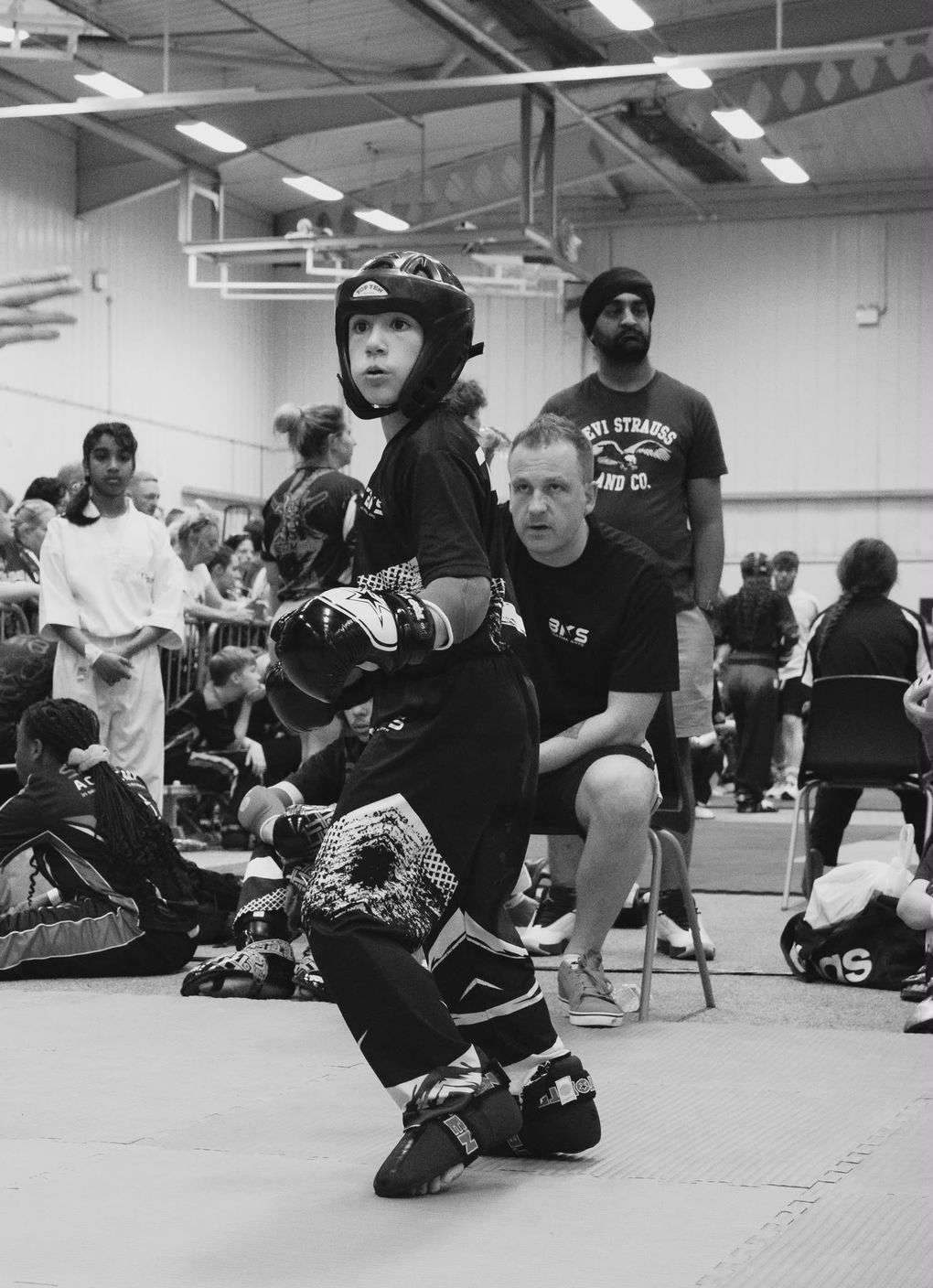 A coach gives instruction to a young martial artist in a competition. Black and white photo.