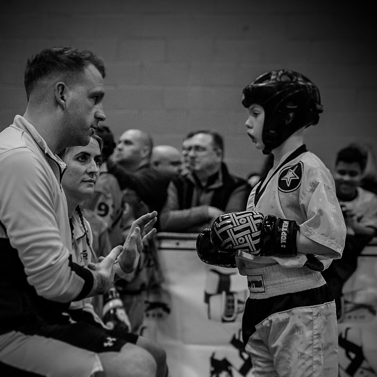 A martial arts coach gives instructions to a young competitor in a competition.