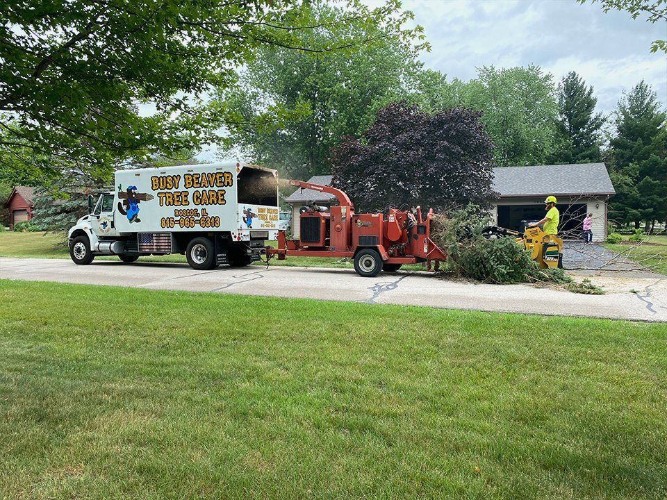 A truck with a tree chipper attached to it is parked in front of a house.