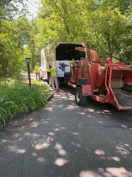 A tree chipper is parked on the side of the road next to a truck.
