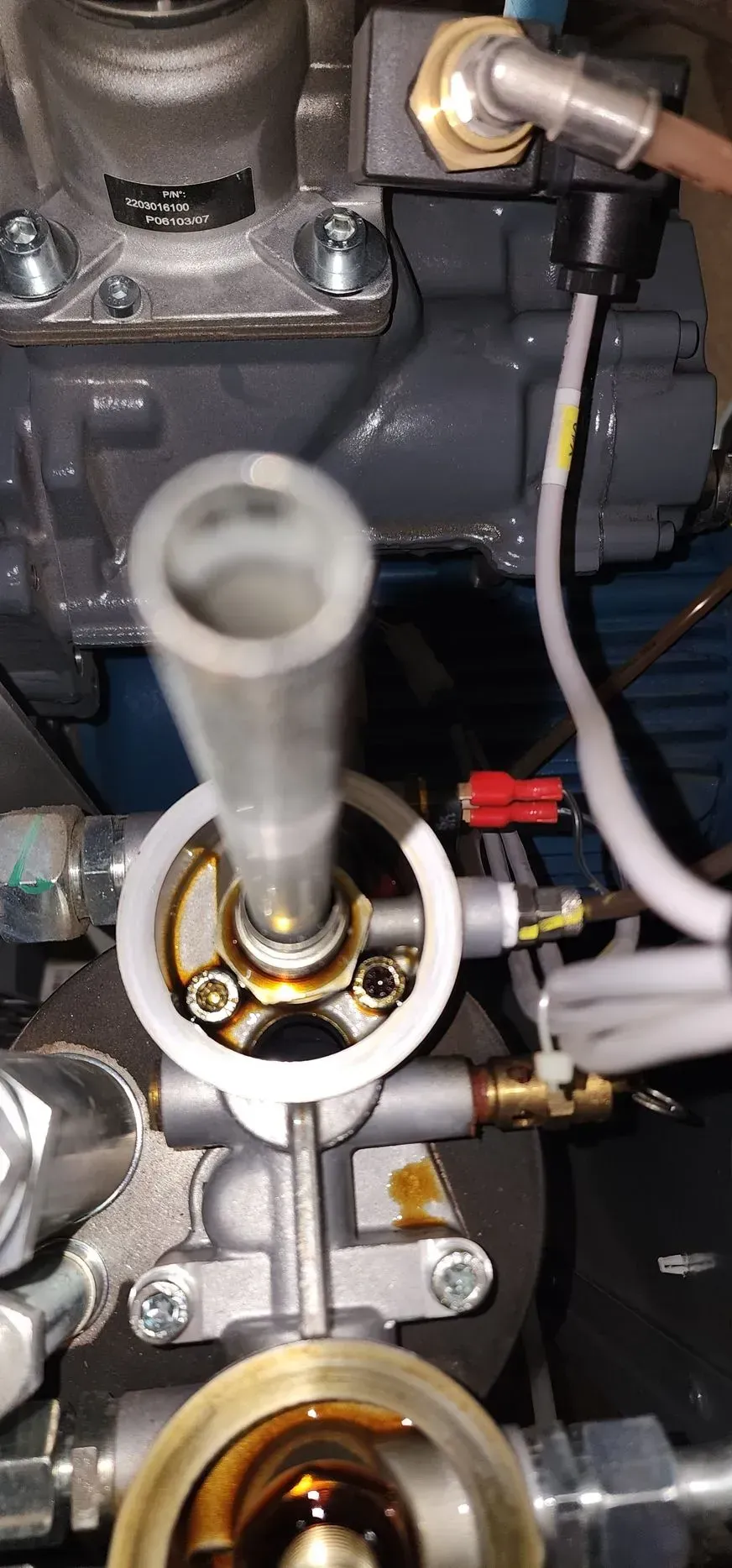 Oil filter assembly with a cylindrical tube in the center and attached lines and hardware.