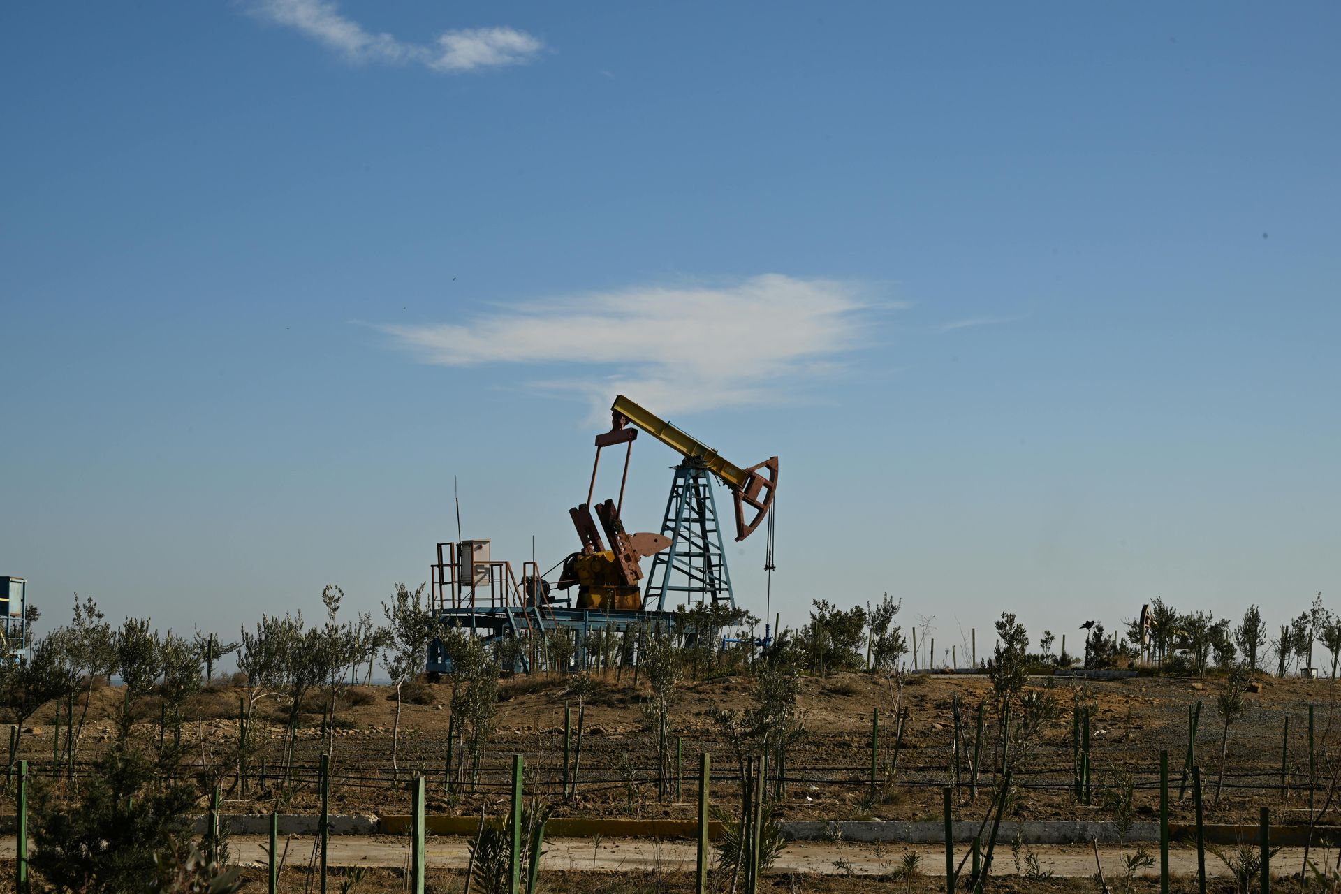 An oil pump is sitting in the middle of a desert.