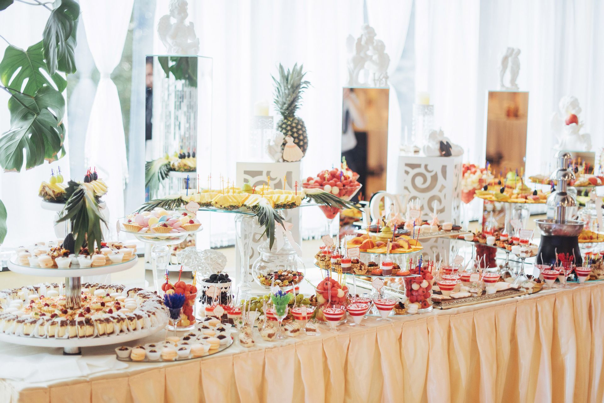 Dessert buffet table with various sweets, including cakes, pastries, and a chocolate fountain, decorated for a special event.