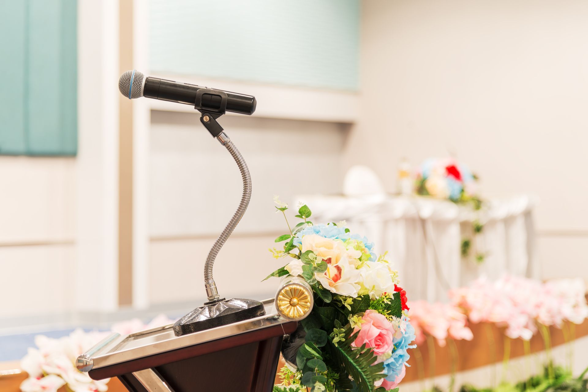 Podium with microphone and floral arrangement in a brightly lit room.
