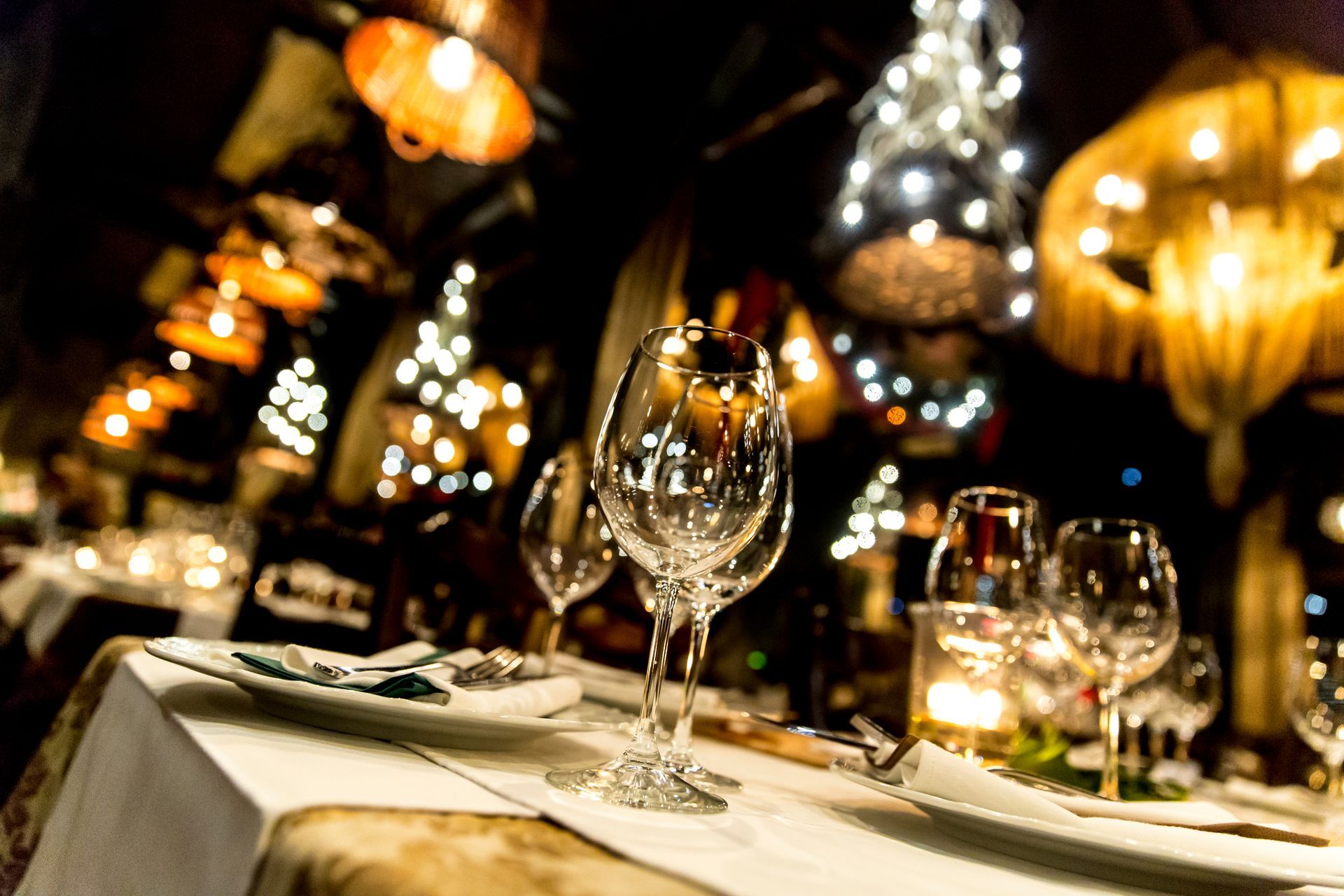 Elegant restaurant table set with wine glasses, lit by decorative overhead lights.