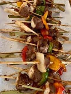 Skewers of grilled meat and vegetables, including peppers and mushrooms.