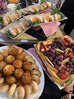 Platters of various foods: sushi rolls, pastries, and a fruit arrangement.