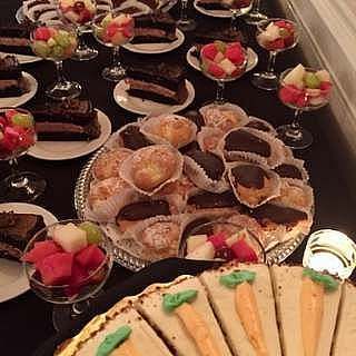 Dessert table with various pastries, fruit cups, and carrot cake slices.
