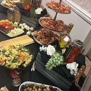 A table set with various dishes like appetizers, bread, pasta salad, and bottles.