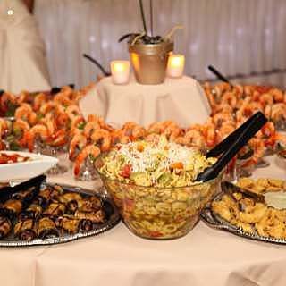 Buffet table with shrimp, pasta salad, and other appetizers.