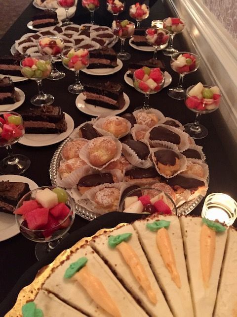 Dessert table with slices of chocolate cake, fruit parfaits, pastries, and carrot cake.