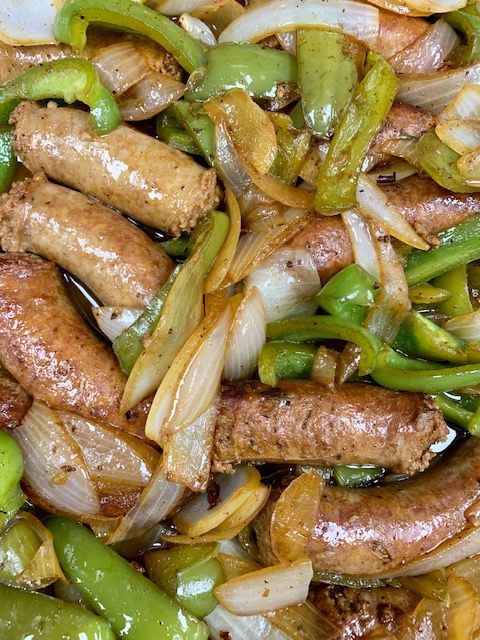 Sausage, green peppers, and onions sautéed in a pan, creating a colorful and delicious meal.