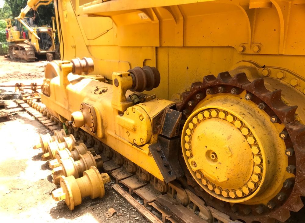 Yellow bulldozer tracks and gears close-up in a construction yard