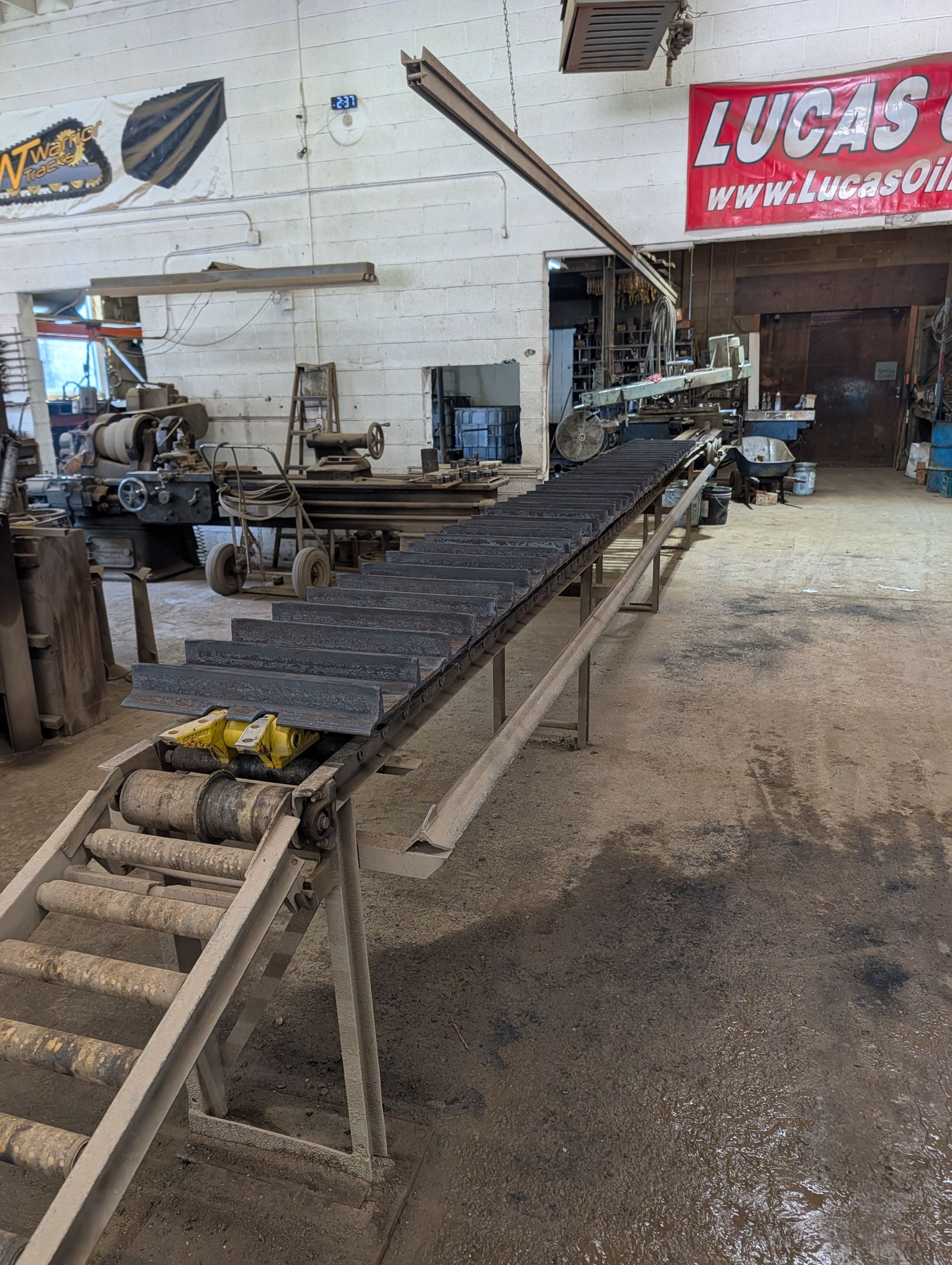 Workshop with a metal workbench and conveyor under a red Lucas sign.