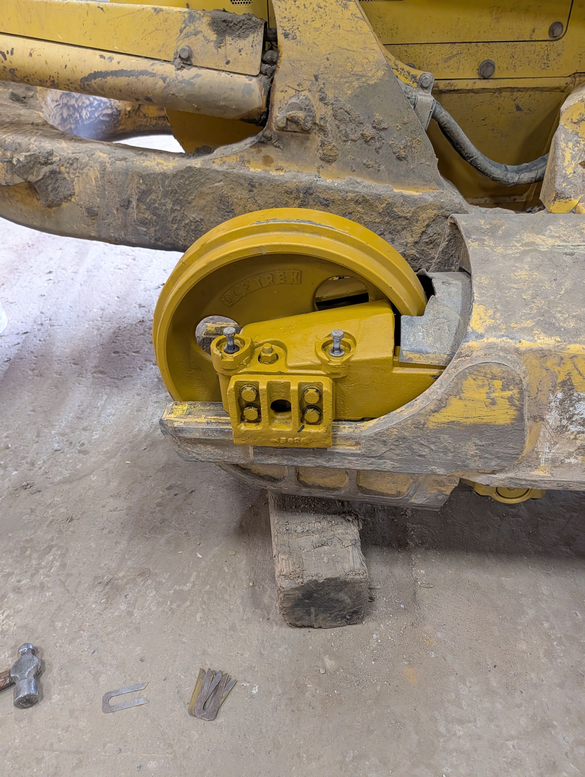 Close-up of a yellow industrial machine part with a small latch and dirt-covered metal surfaces.