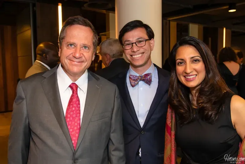A man in a suit and tie is posing for a picture with two other people.