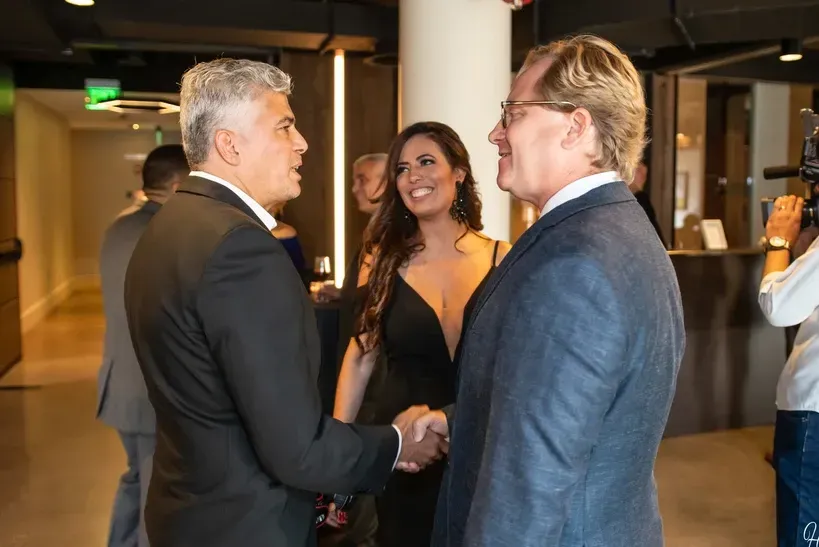 A man in a suit is shaking hands with a woman in a black dress.