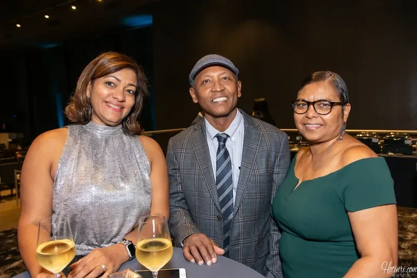 A man and two women are posing for a picture at a party.