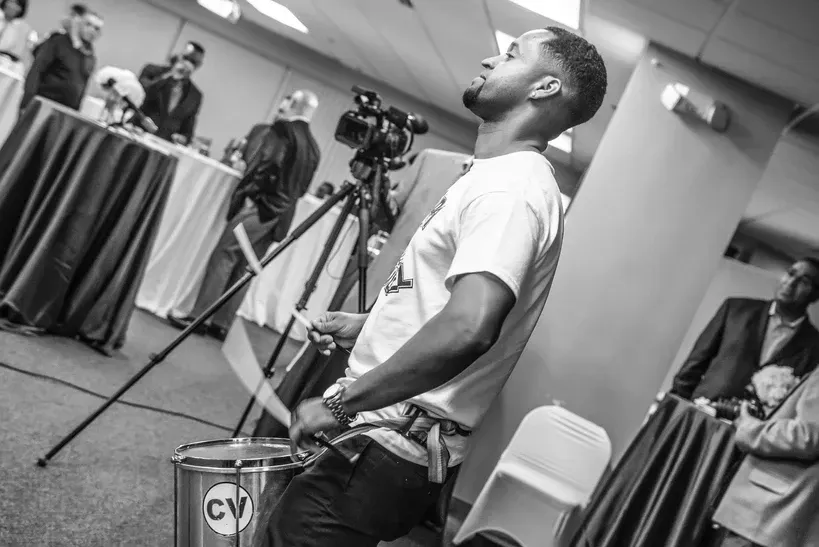 A man is playing a drum in a black and white photo.