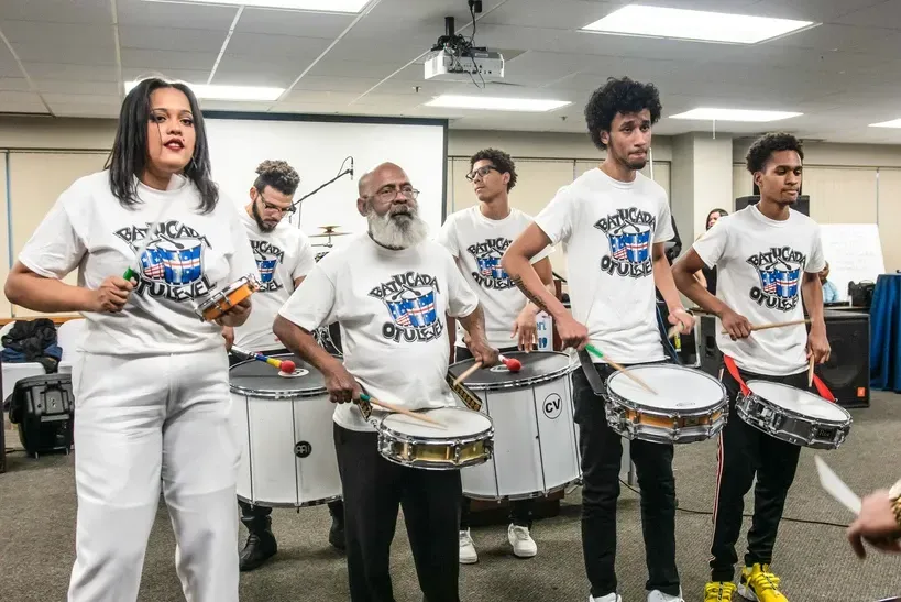 A group of people are playing drums in a room.