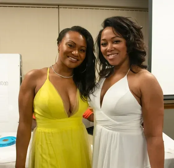 Two women are posing for a picture and one is wearing a yellow dress