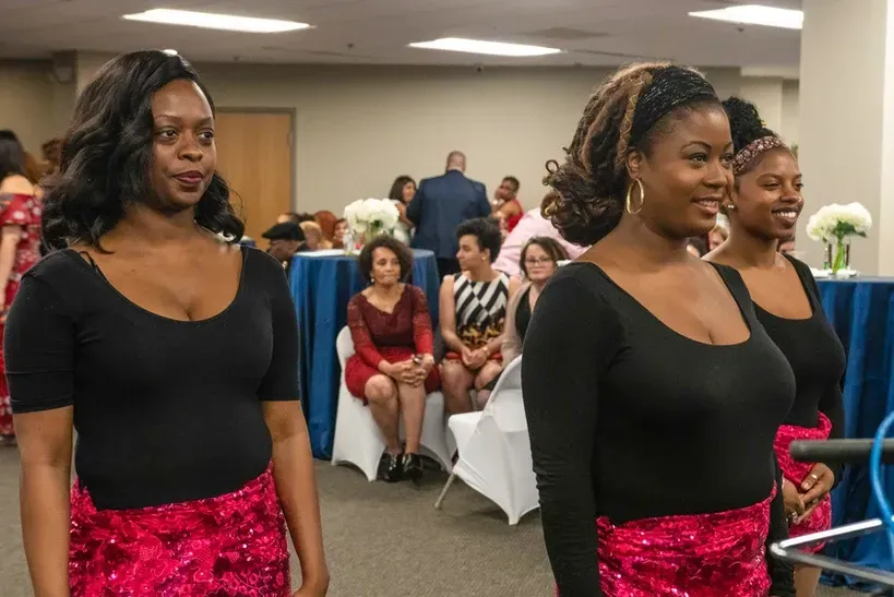 Three women are standing next to each other in a room.