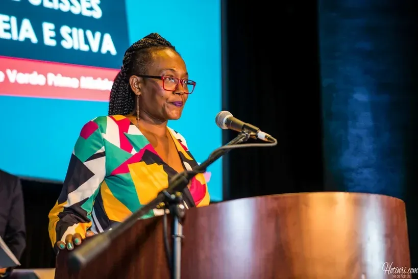 A woman is standing at a podium speaking into a microphone.