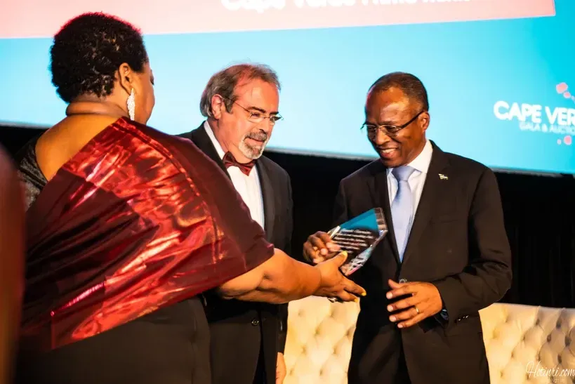 A woman in a red dress is giving an award to a man in a suit.