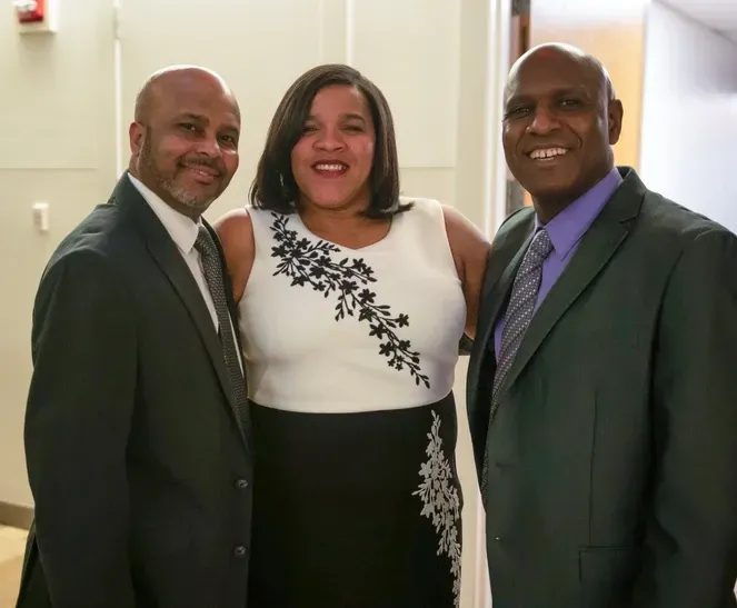 Two men and a woman are posing for a picture together