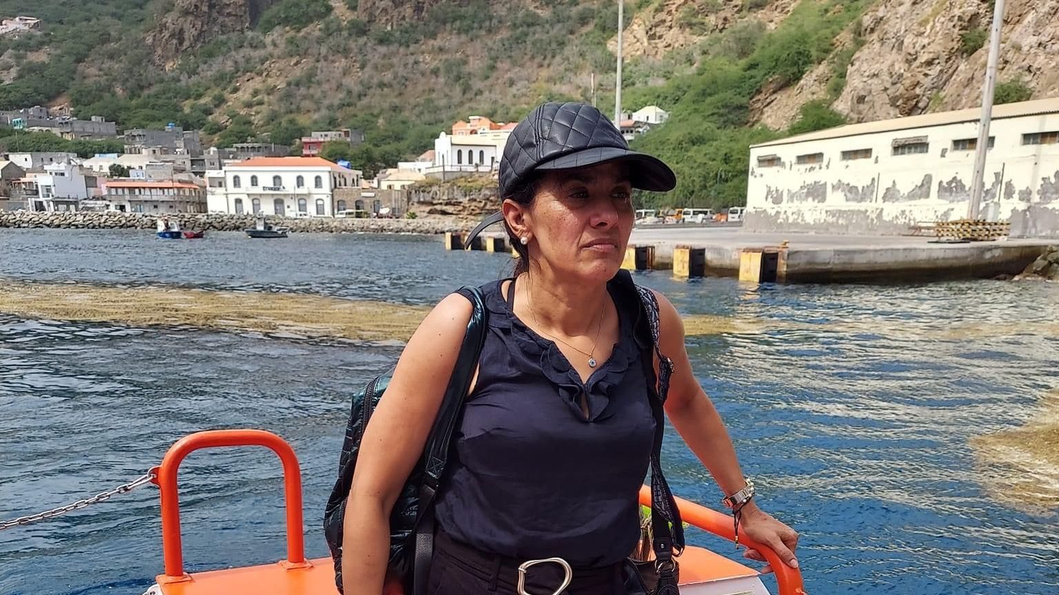 A woman is standing on the back of a boat in the water.