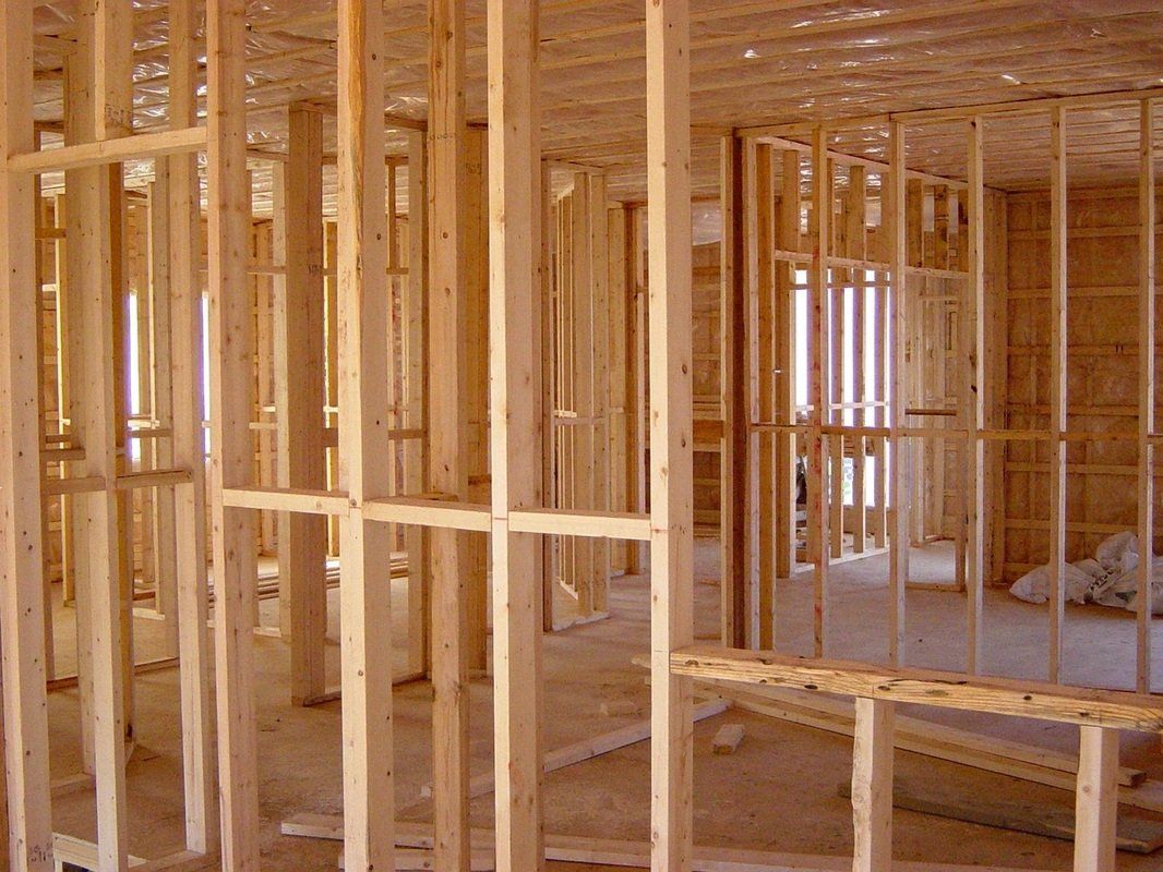 Wooden framing for a house under construction, showing interior wall studs and structural beams.