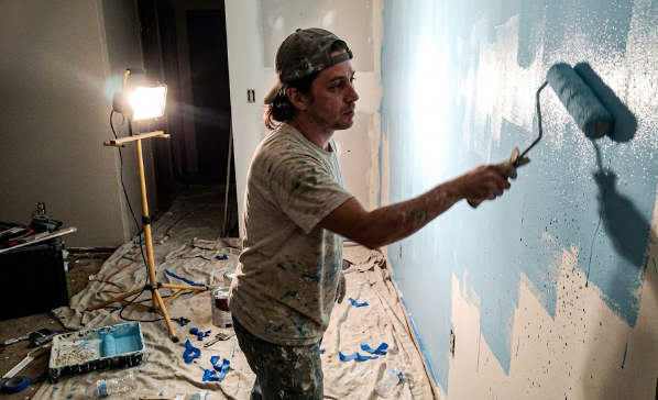 Professional painter applying fresh blue paint to a living room wall in Spokane.