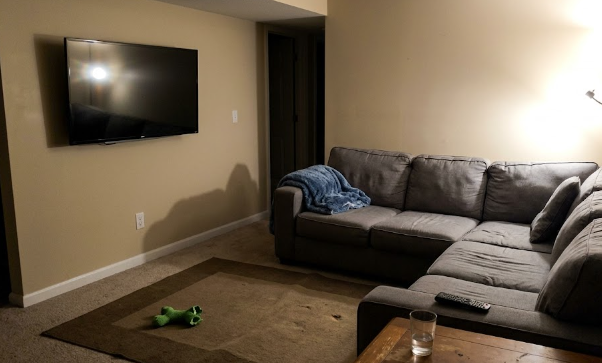 A cozy finished basement family room in Spokane with a gray couch and TV.