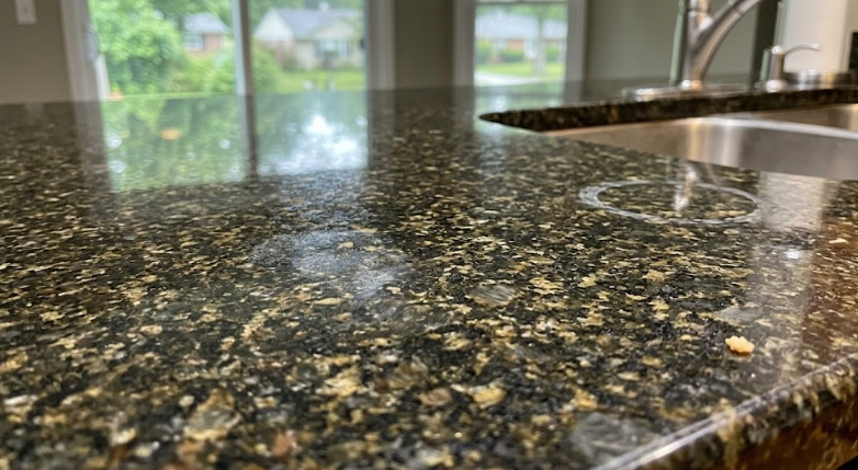 Close-up detail of durable dark granite countertop surface with gold and brown speckles.