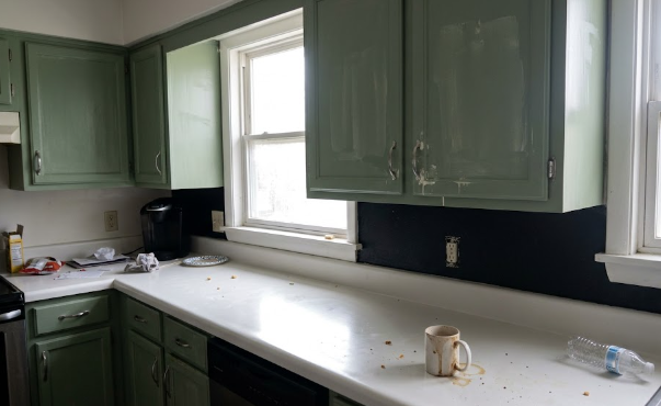 Modern kitchen with freshly painted sage green cabinets and white countertops.