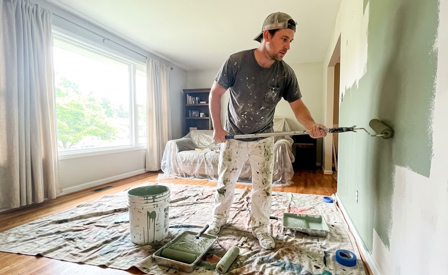 Professional interior painter applying sage green paint to a living room wall in Spokane WA.