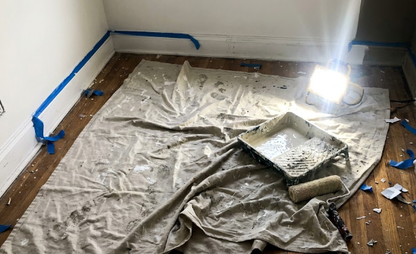Organized painting setup with drop cloths and painter's tape protecting a home floor.