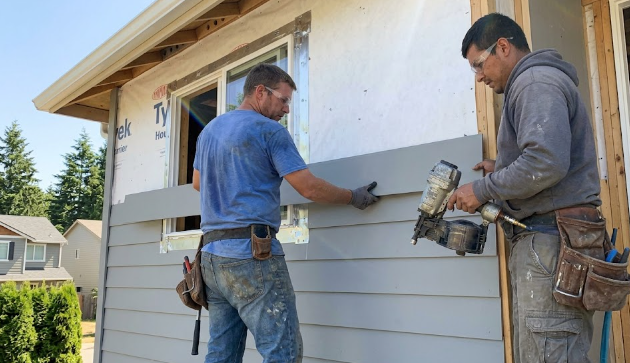 Friendly and professional siding contractors installing new exterior cladding on a house.