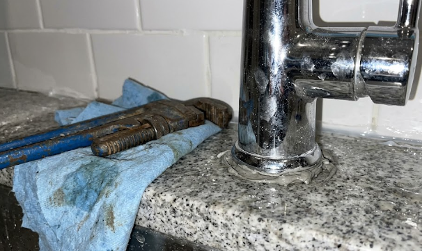 Professional contractor installing a new kitchen sink faucet and granite countertops.